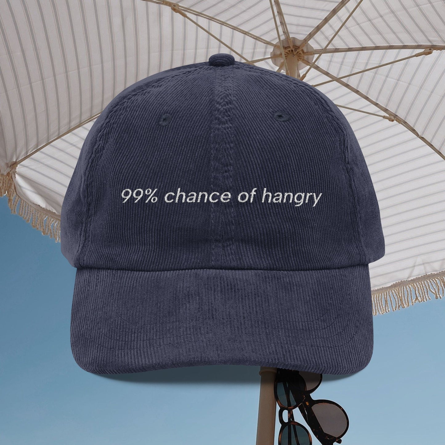 Navy blue cap with '99% chance of hangry' text under a white umbrella.
